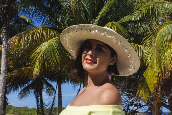 Modelo posando un sombrero para dama en la playa